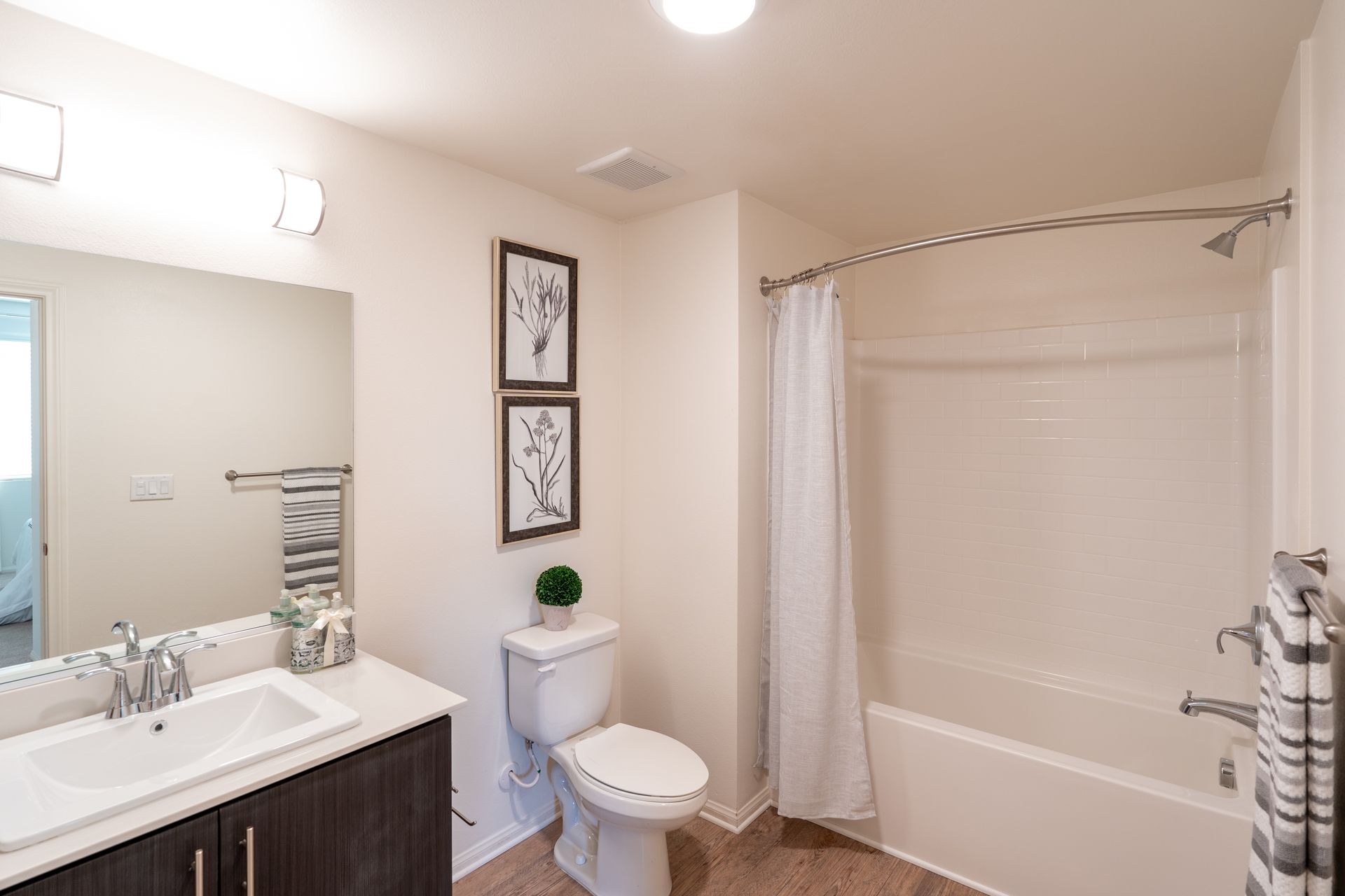 A bathroom and vanity mirror and sink and toilet and tub with shower