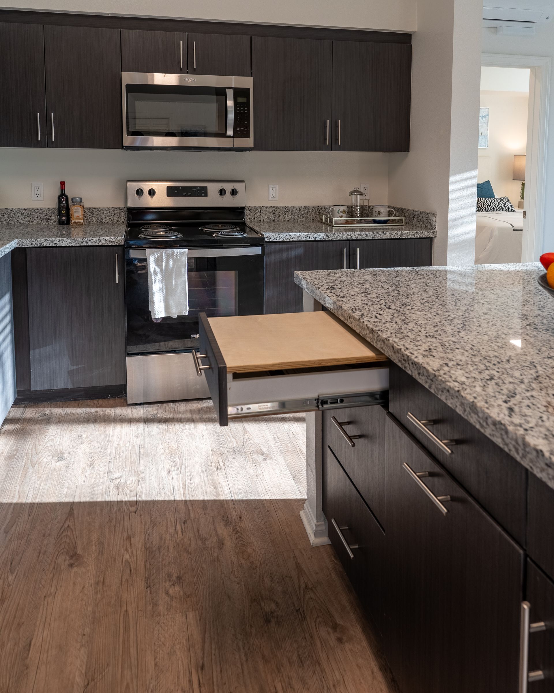 A kitchen with a center island and stainless steel appliances and a drawer cutting board
