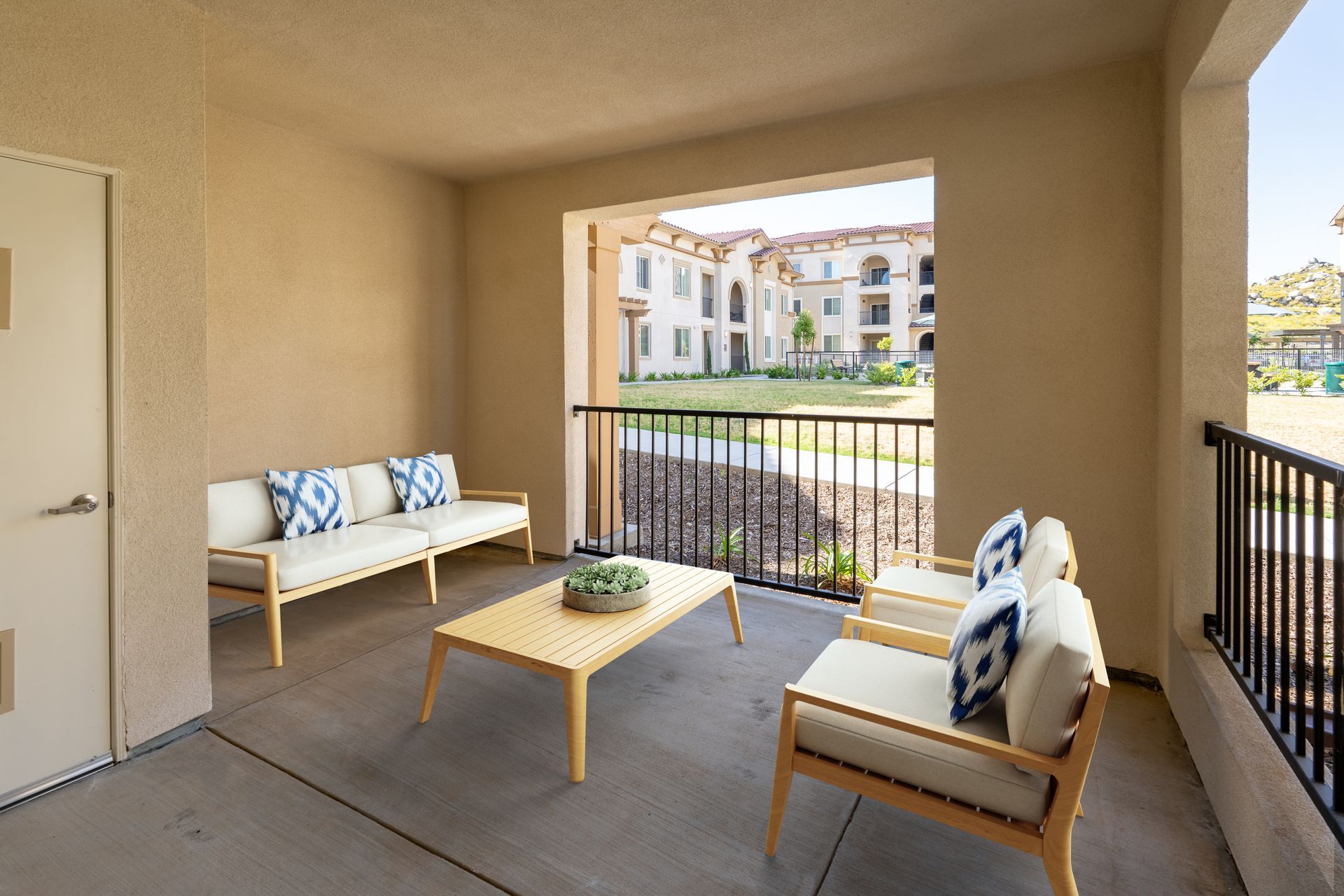 A patio with railing and a view outside with chairs and a table