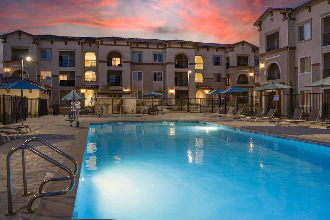 a large building with a pool and umbrellas in front of it