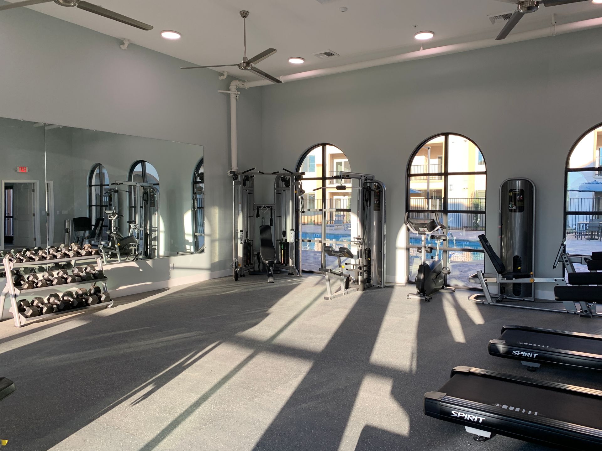 a large gym with a treadmill , dumbbells , and a mirror .