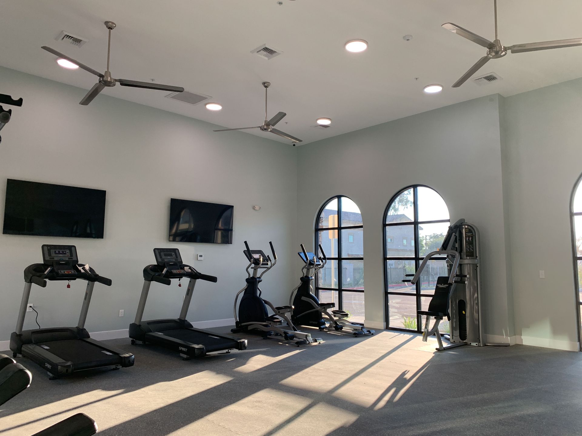 a gym with treadmills , exercise bikes , a television and a ceiling fan .