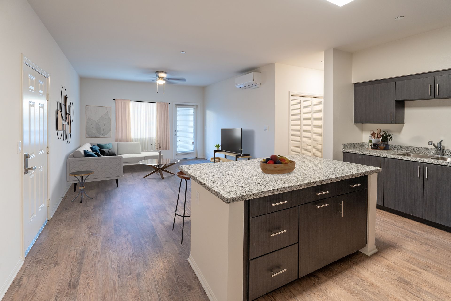 A kitchen with a center island and view of the living room with a couch