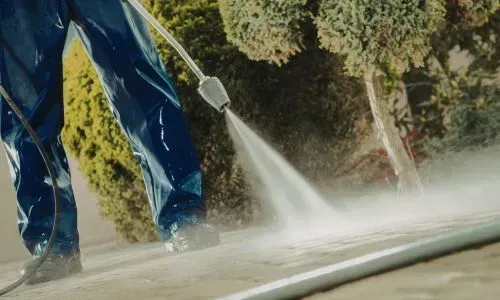 Power washing a concrete driveway to remove surface buildup during a residential clean in Wakari, Dunedin.