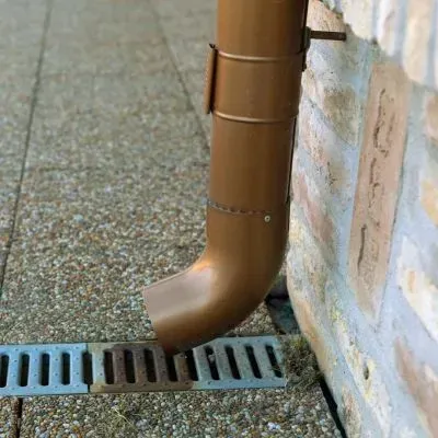 Downpipe directing water into the ground drain, showing proper roof drainage away from a Dunedin home.