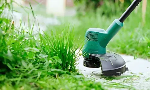 Lawn and garden care services are occurring in Corstorphine, Dunedin. A local gardener using a weed whacker.