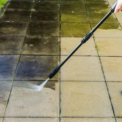 Water blasting a patio surface to remove grime and brighten outdoor tiles in Helensburgh, Dunedin.