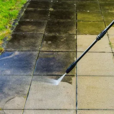 Pressure washing moss and grime from residential paving to restore the surface finish.