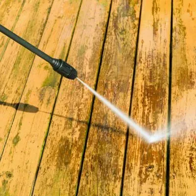 Controlled pressure washing of a timber deck to remove grime while protecting the wood surface.