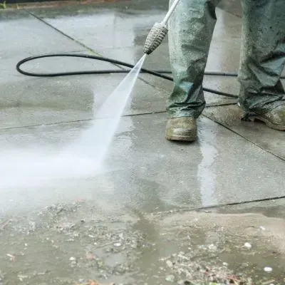 Pressure washing a concrete surface in Dunedin under local water-use restrictions, using controlled water flow.