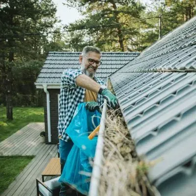 Spout-cleaning expert removing gutter debris by hand, demonstrating safe, controlled cleaning for reliable roof drainage.