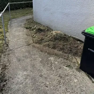 After: Overgrown weeds and garden waste build up, and garden clearance services beside a residential home in North Dunedin.