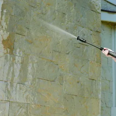 Pressure washing a retaining wall to lift surface build-up during a clean in Sawyers Bay, Dunedin.