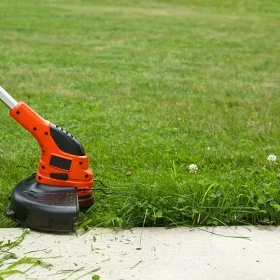 Edging a verge with a trimmer along a Dunedin curb for tidy, safe borders.