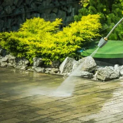 Careful pressure washing of residential pavers near garden landscaping in Dunedin using safe exterior cleaning practices.