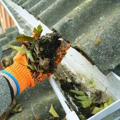 Removing debris from a gutter in Dunedin to prevent contaminants from entering the stormwater system.