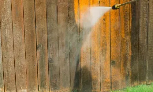 Water blasting a timber fence to remove moss and grime during an exterior clean in Sunnyvale, Dunedin.