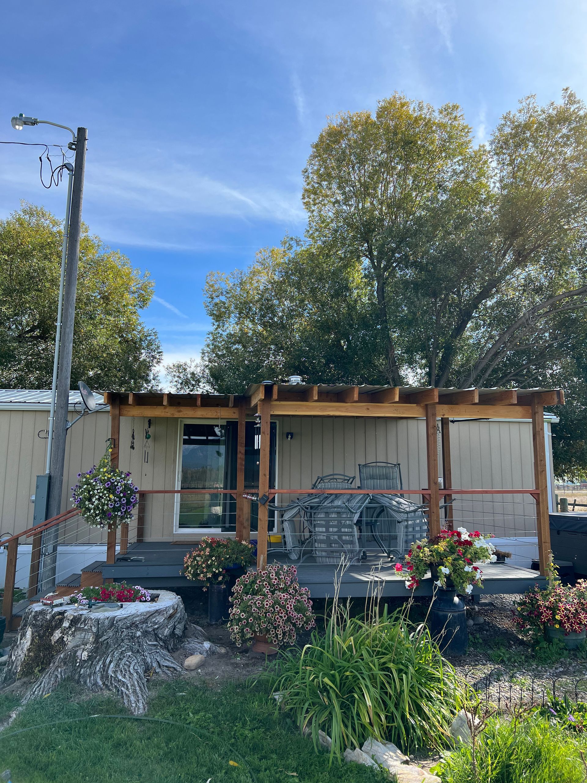 A mobile home with a pergola and a deck in front of it.