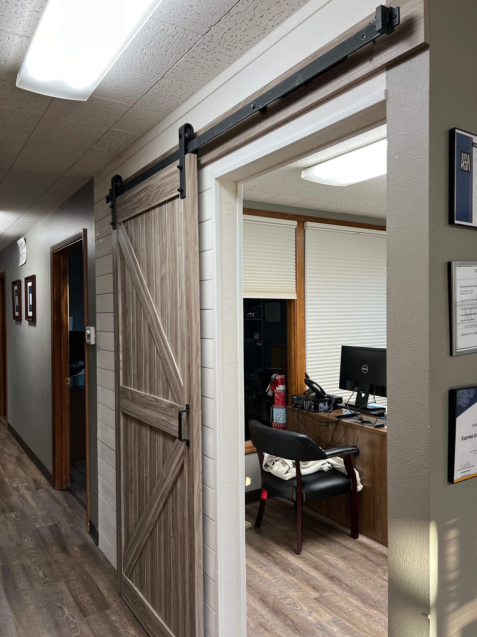 A hallway with a sliding barn door leading to an office