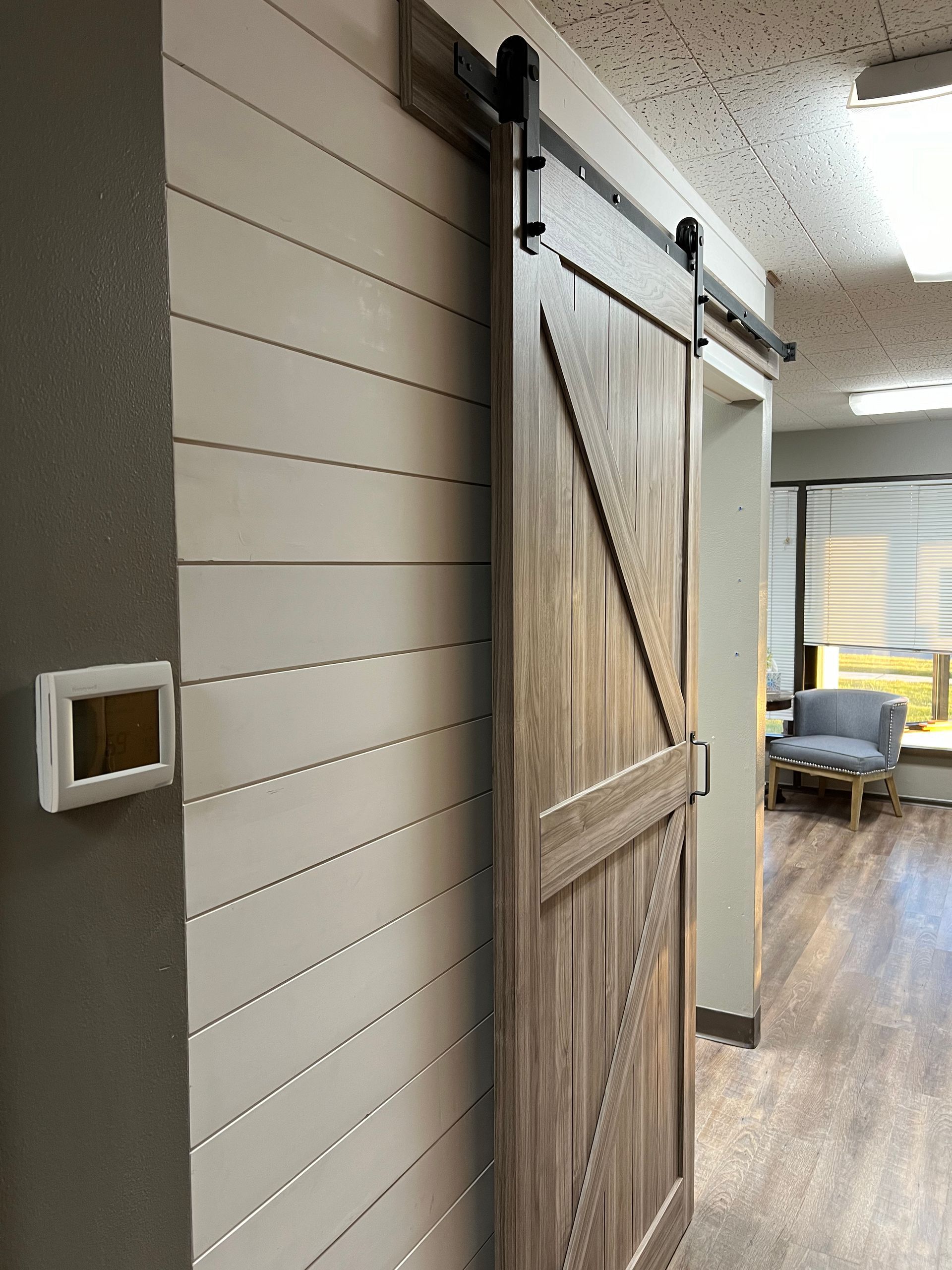 A sliding barn door is hanging on a wall in a hallway.