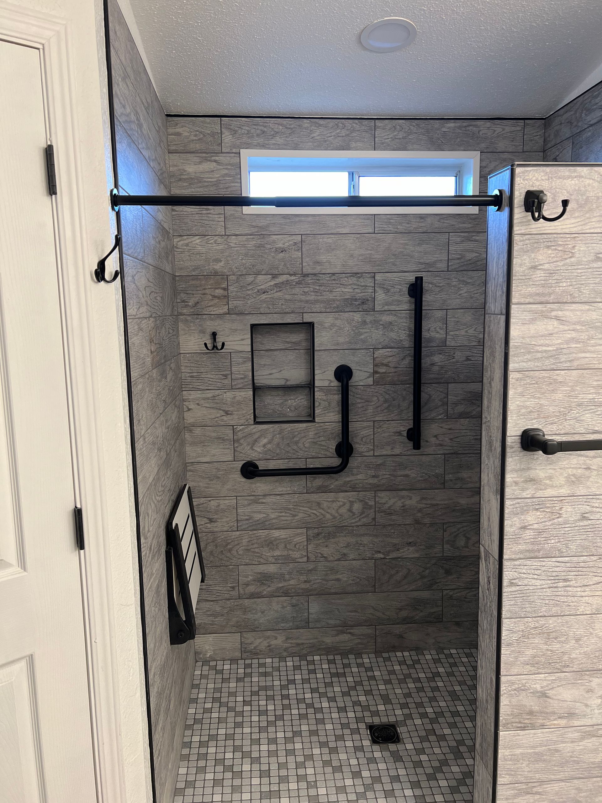 A bathroom with a walk in shower and a window.