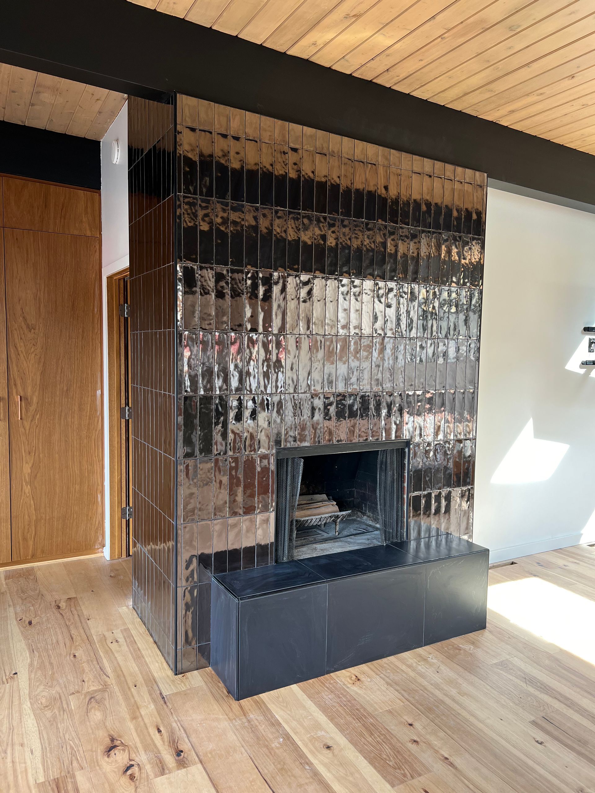 A living room with a fireplace and a mirrored wall