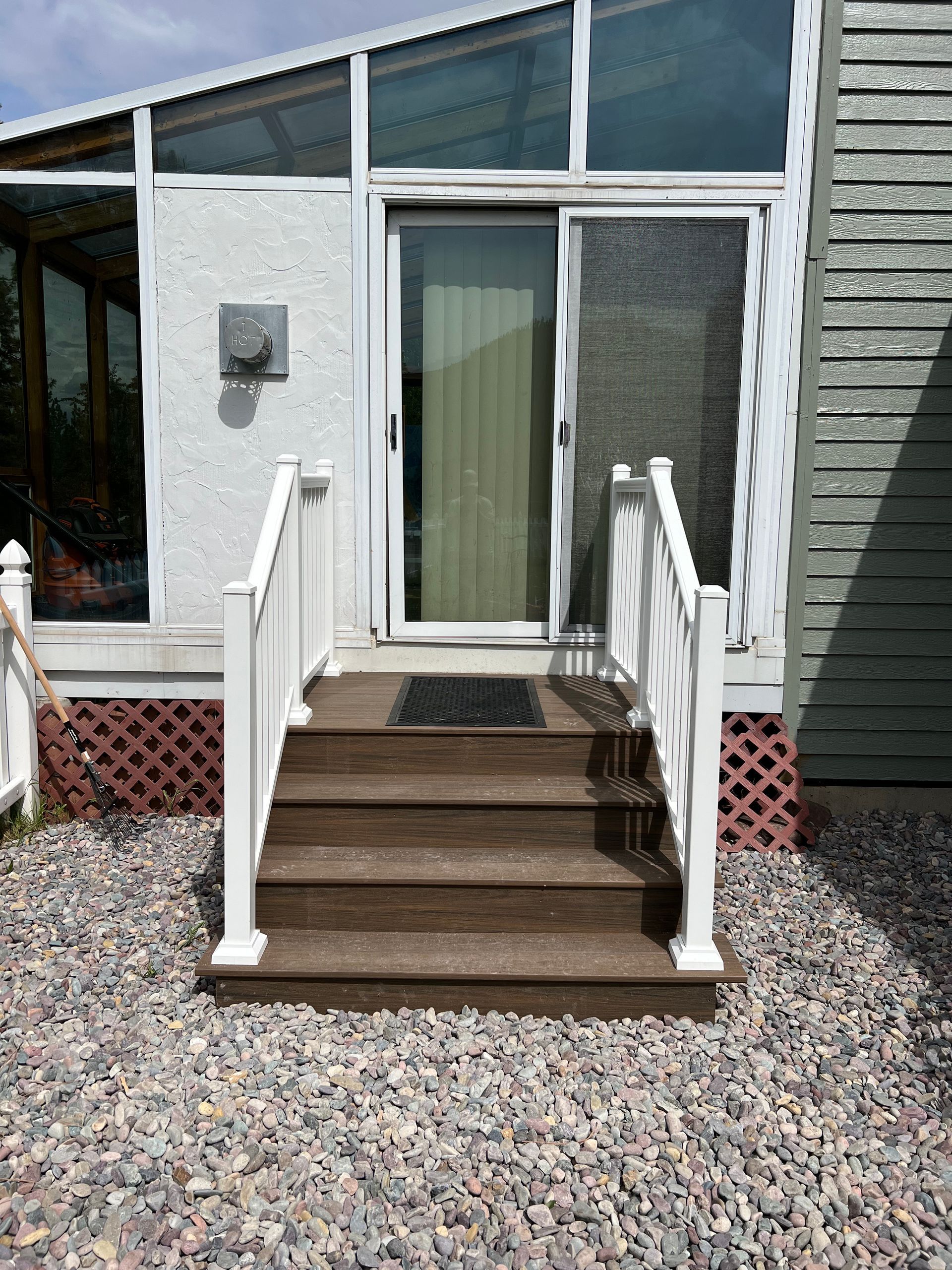 A wooden deck with stairs leading up to a sliding glass door.