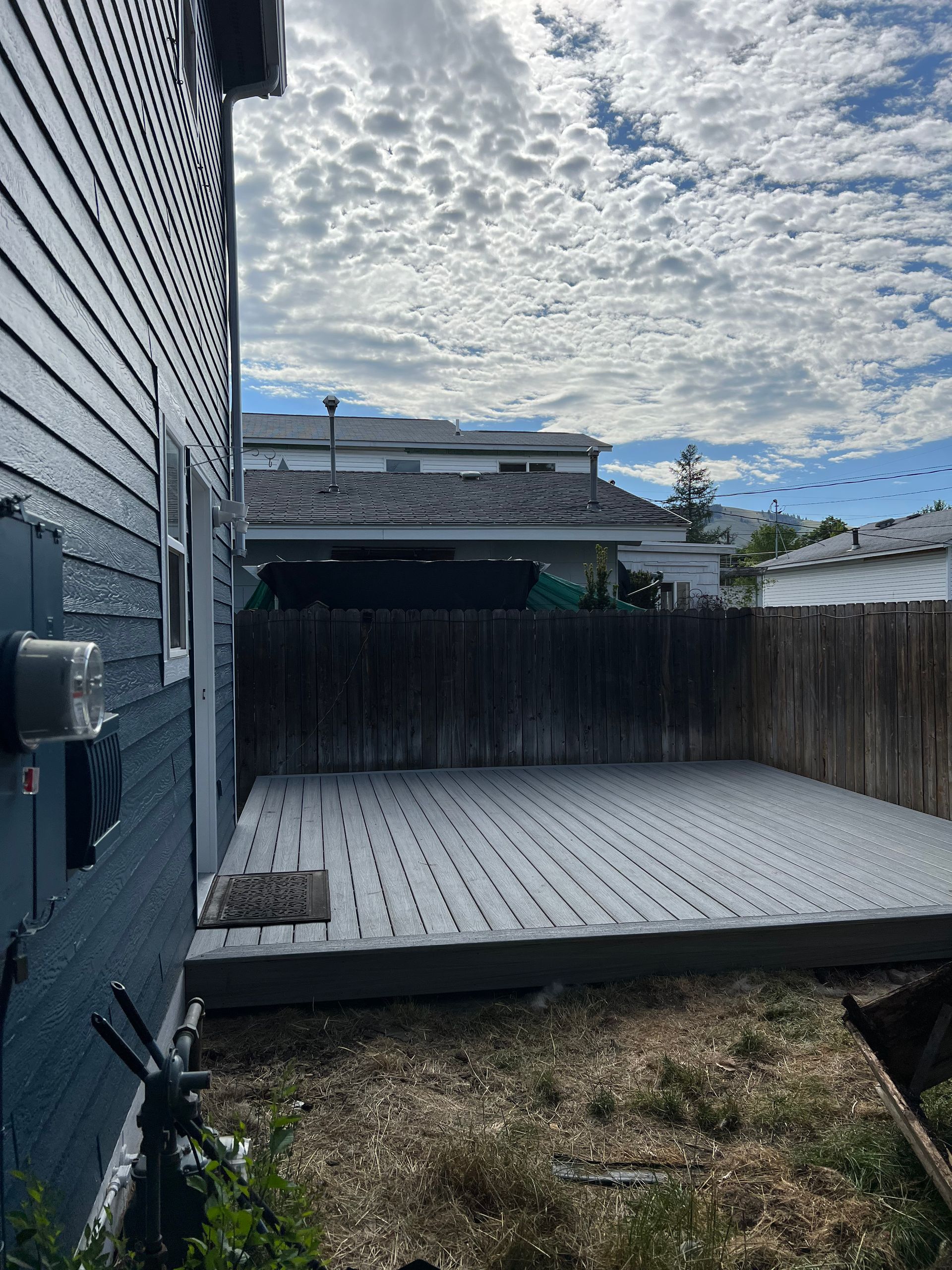 A white deck is sitting in the backyard of a house.