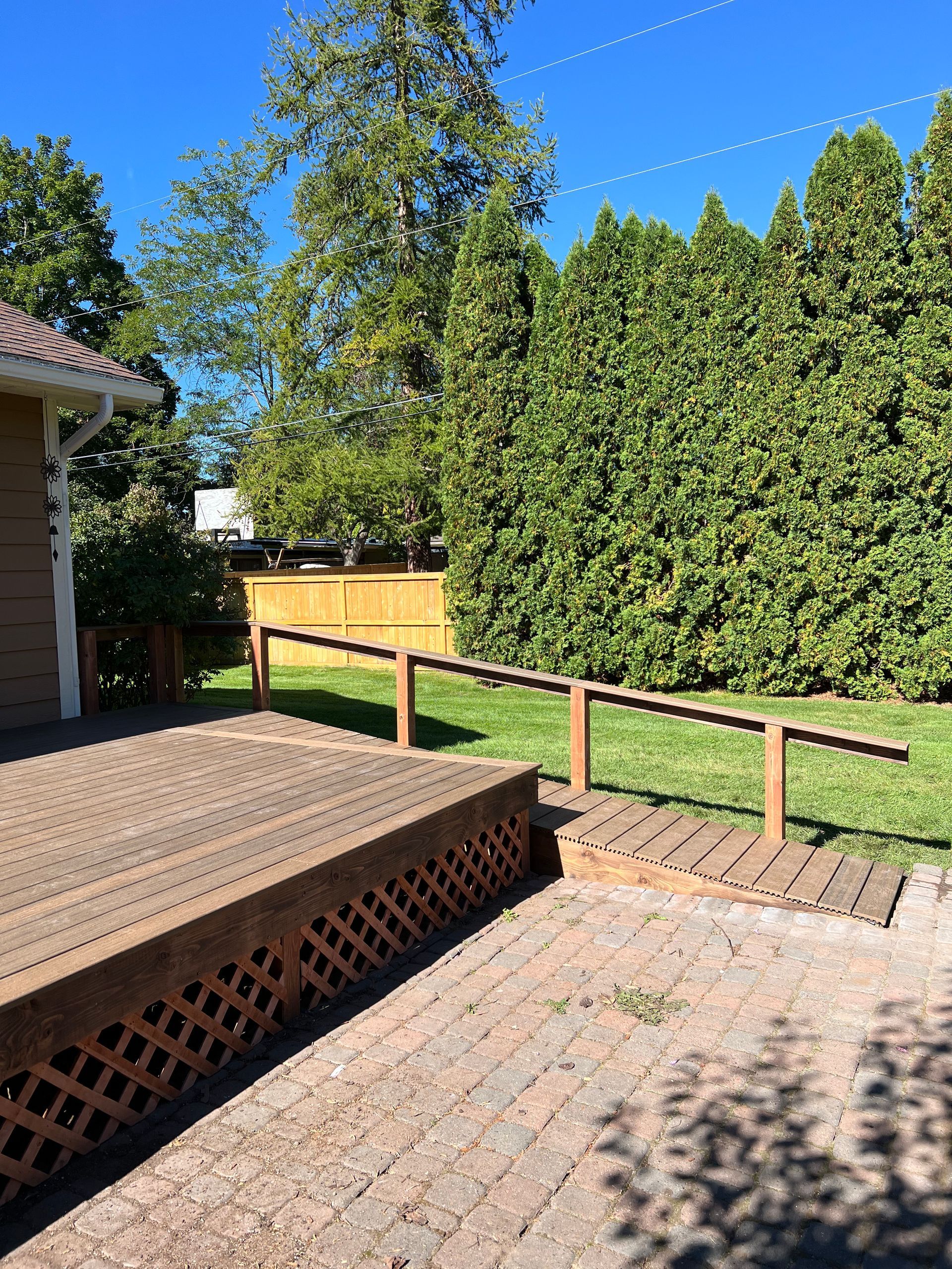 A wooden deck with a brick walkway leading to it