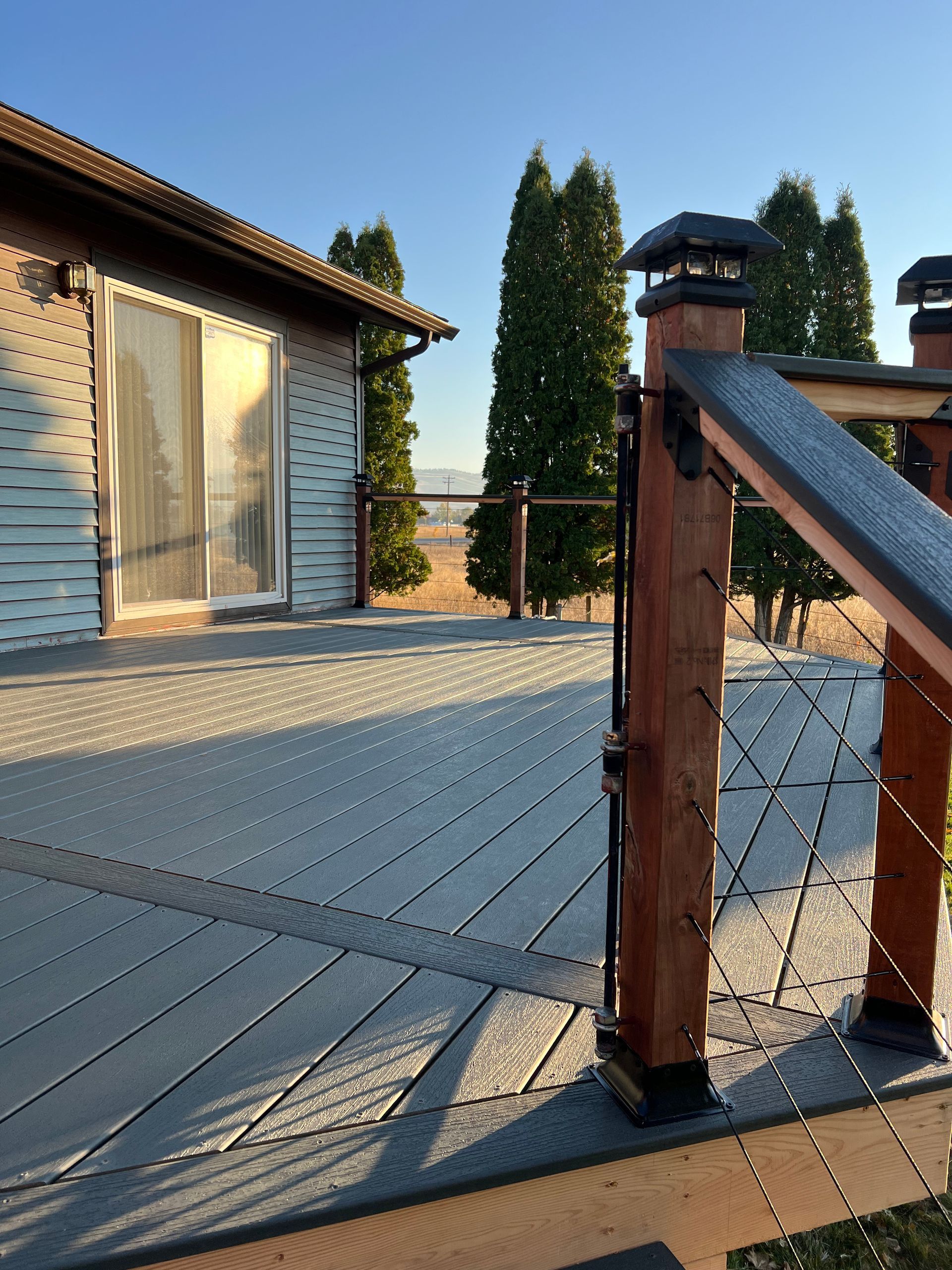 A deck with a wooden railing and a house in the background
