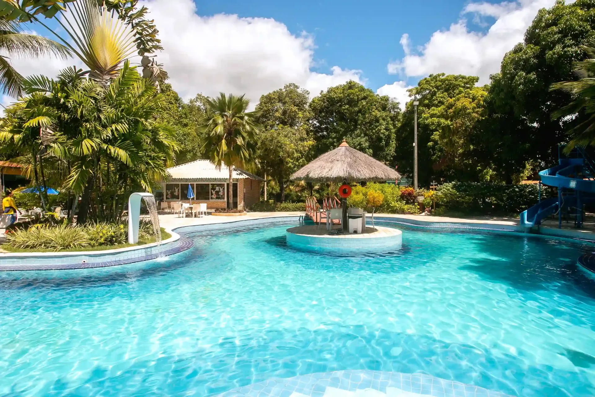 Uma grande piscina rodeada de árvores e um toboágua-hotel-praia-dourada-maragogi-park