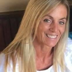 A woman with long blonde hair is smiling for the camera.