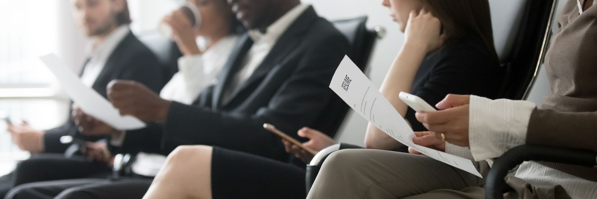 A people seated in a waiting area holding resumes and phones while preparing for job interviews A people seated in a waiting area holding resumes and phones while preparing for job interviews