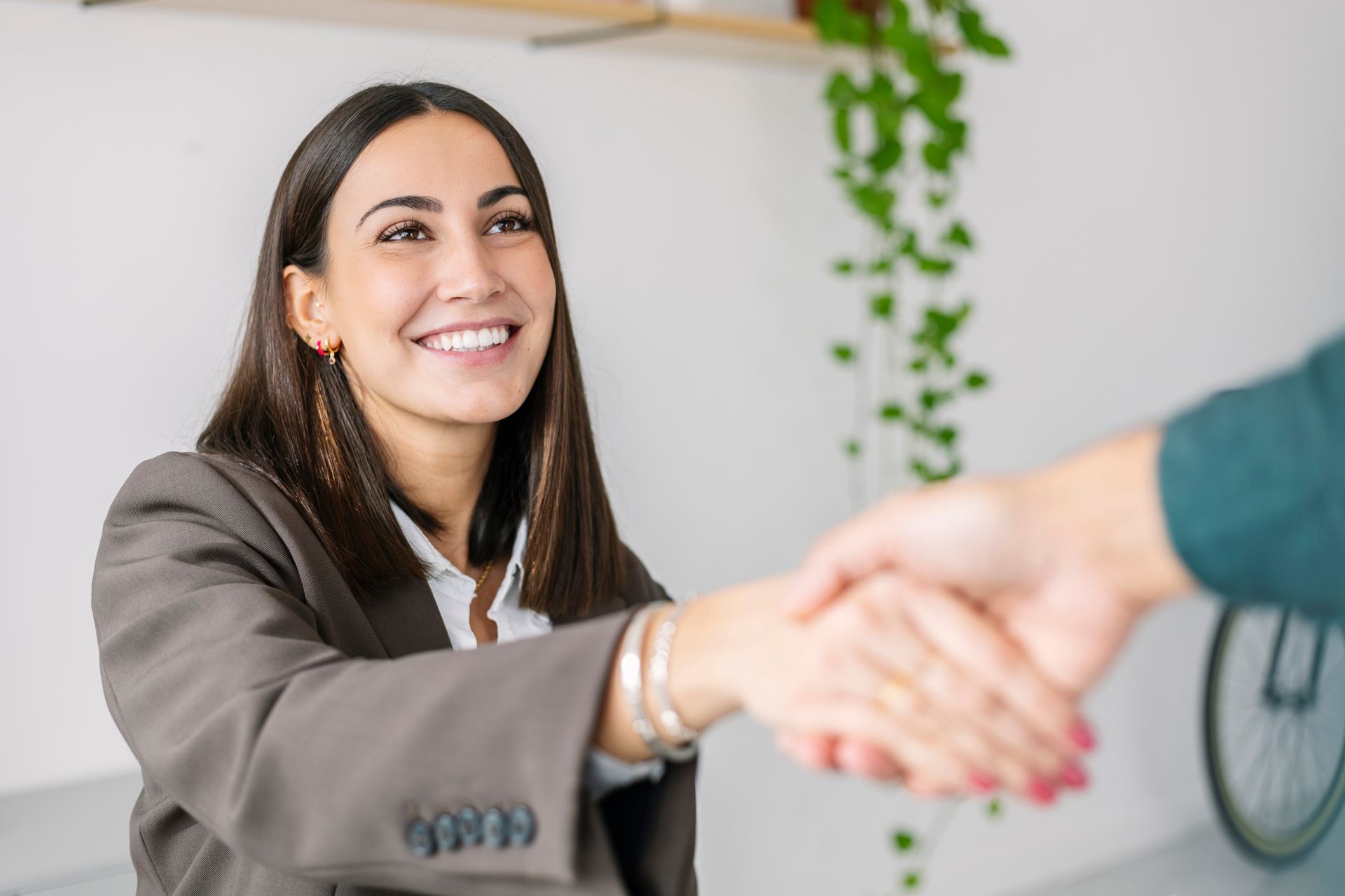Happy recruiter shaking hand with candidate in office.