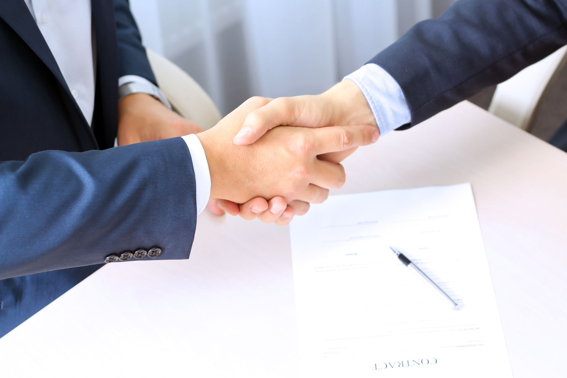 Close-up of a handshake between two people wearing suits.