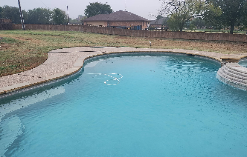 A backyard pool with clear blue water and a tan concrete border.