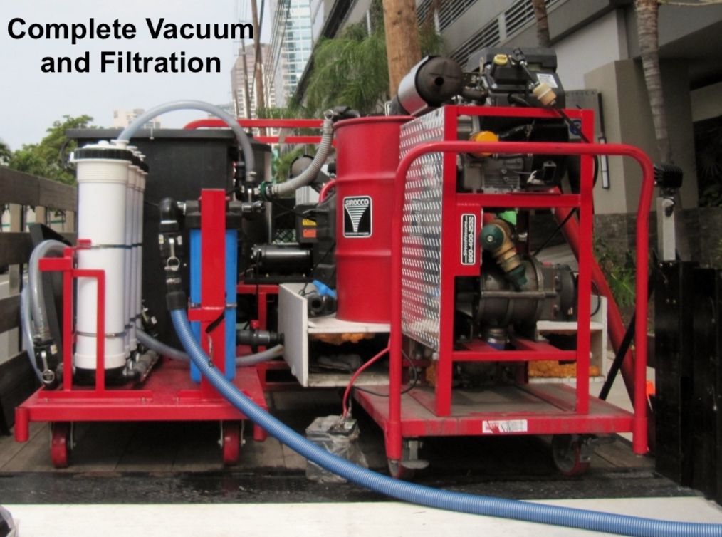 A red, industrial-grade mobile vacuum and filtration machine with hoses and tanks, positioned outdoors on a paved area.