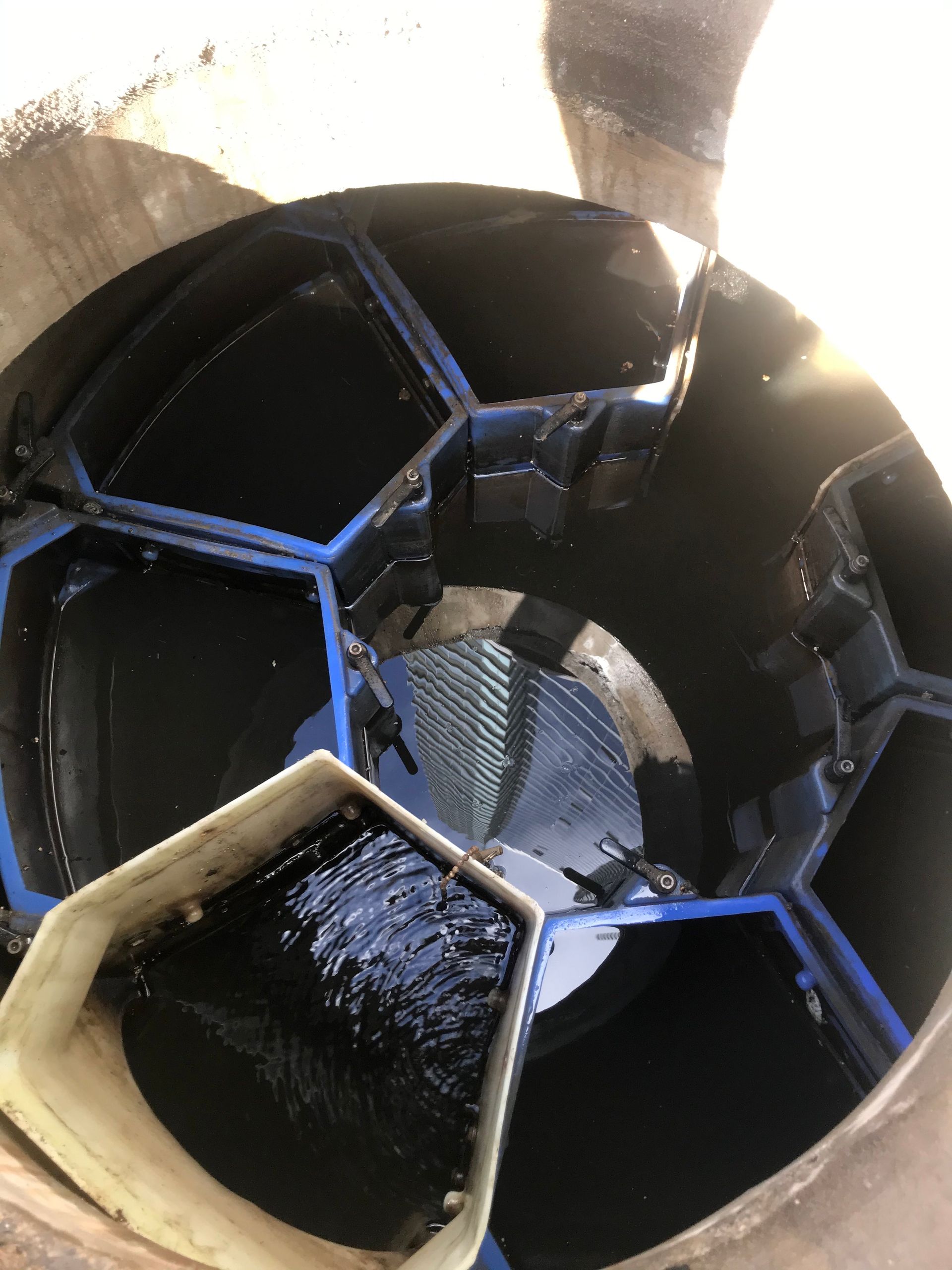 Inside view of a large black and blue hexagonal structure with a circular opening and bright light above.