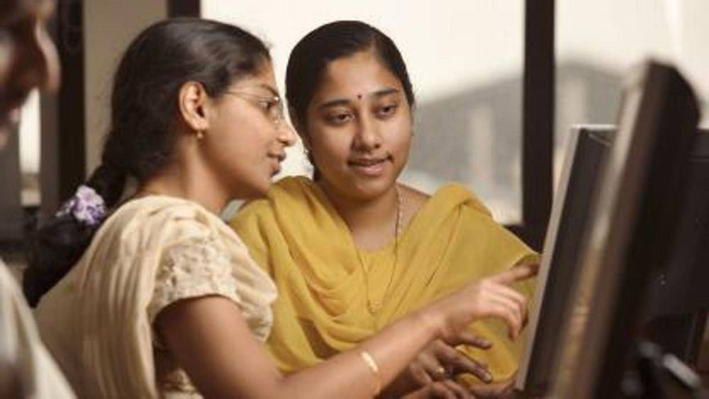 Two women are looking at a computer screen together.
