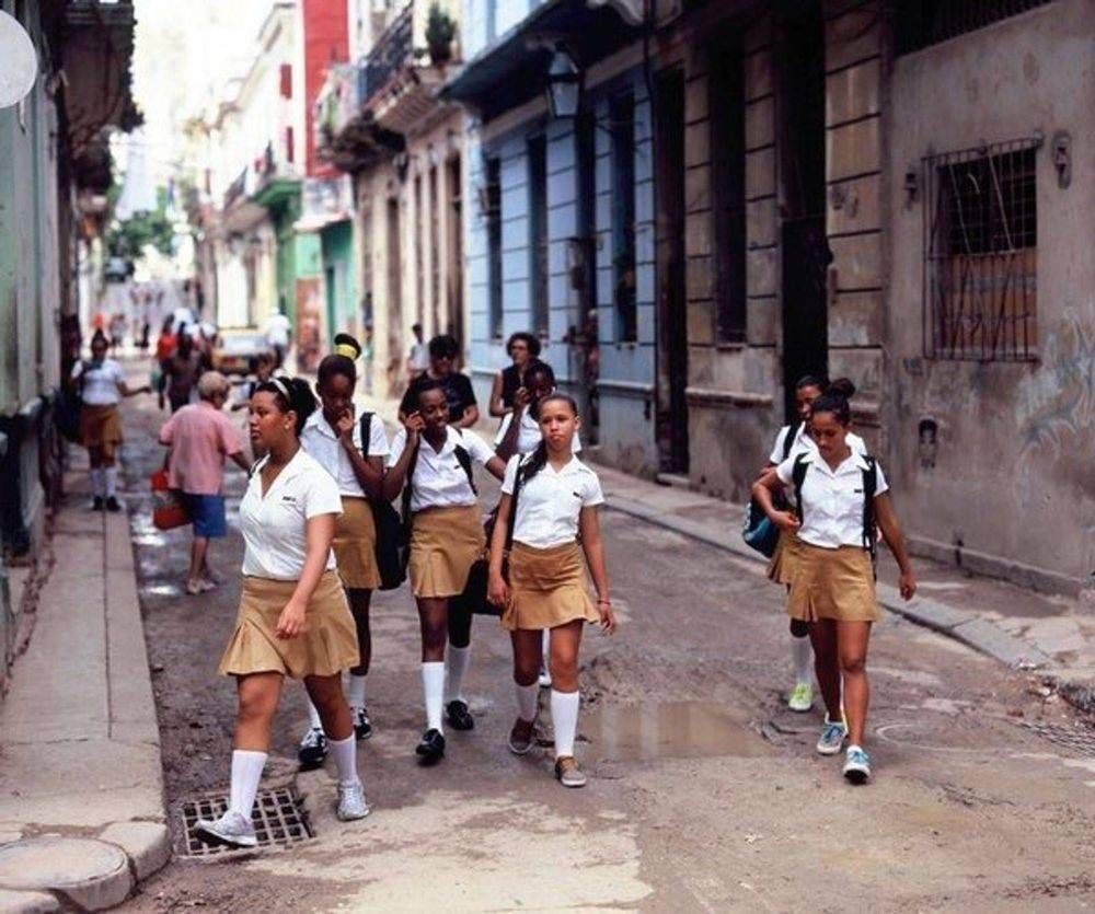 A group of girls in school uniforms are walking down a street.