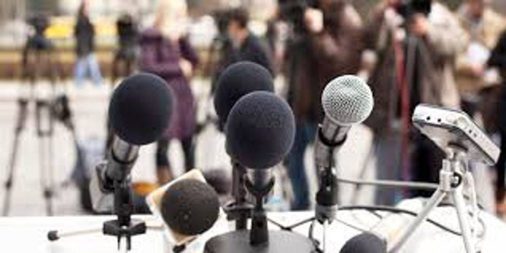 A group of microphones are sitting on a table in front of a crowd of people.