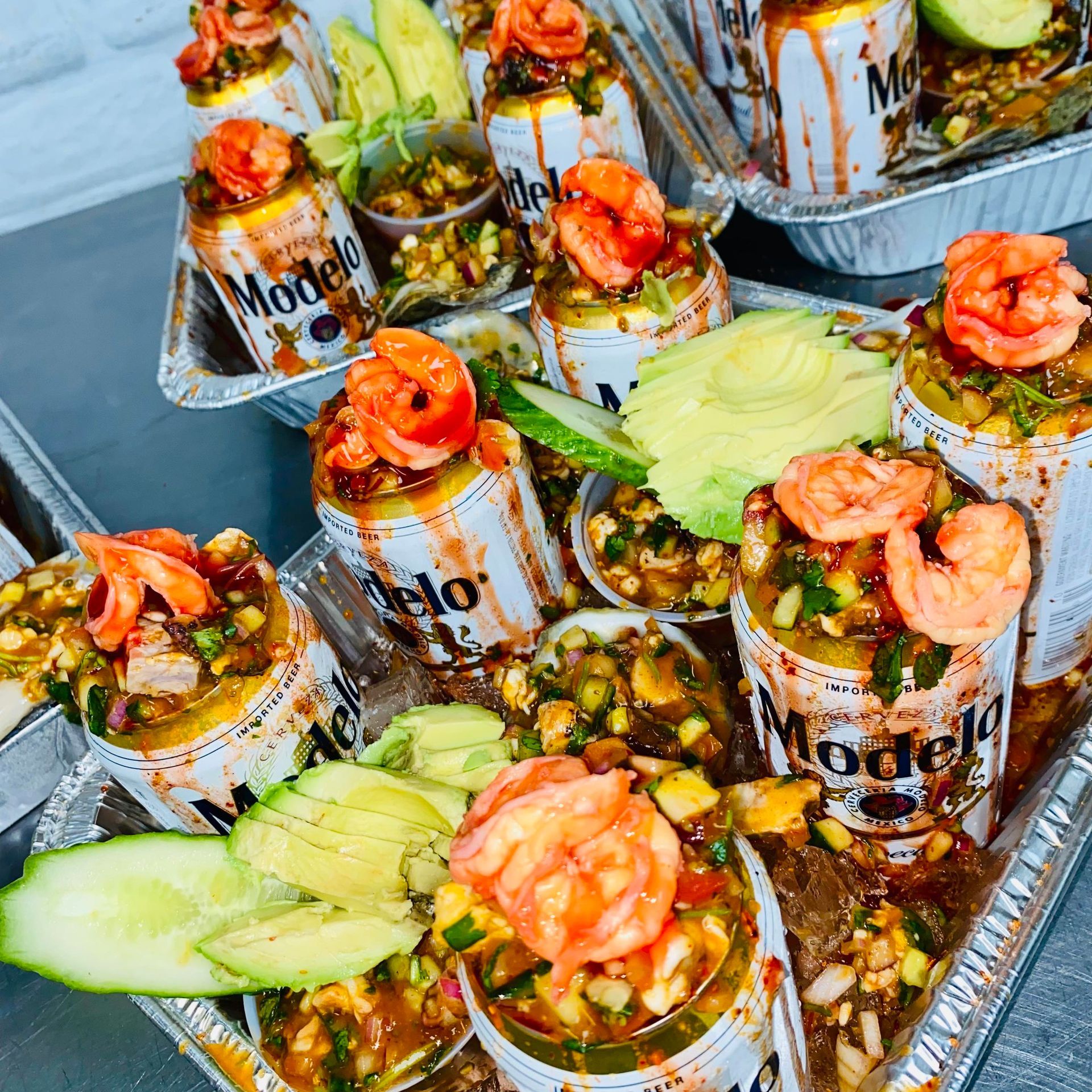 A tray of food with shrimp , avocado , and cucumbers on a table.