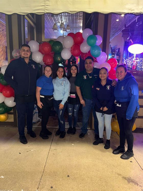 A group of people are posing for a picture in front of balloons.