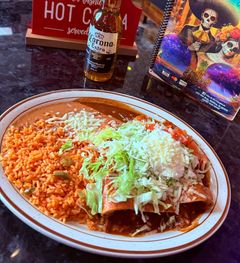 A plate of food with rice and enchiladas on a table.