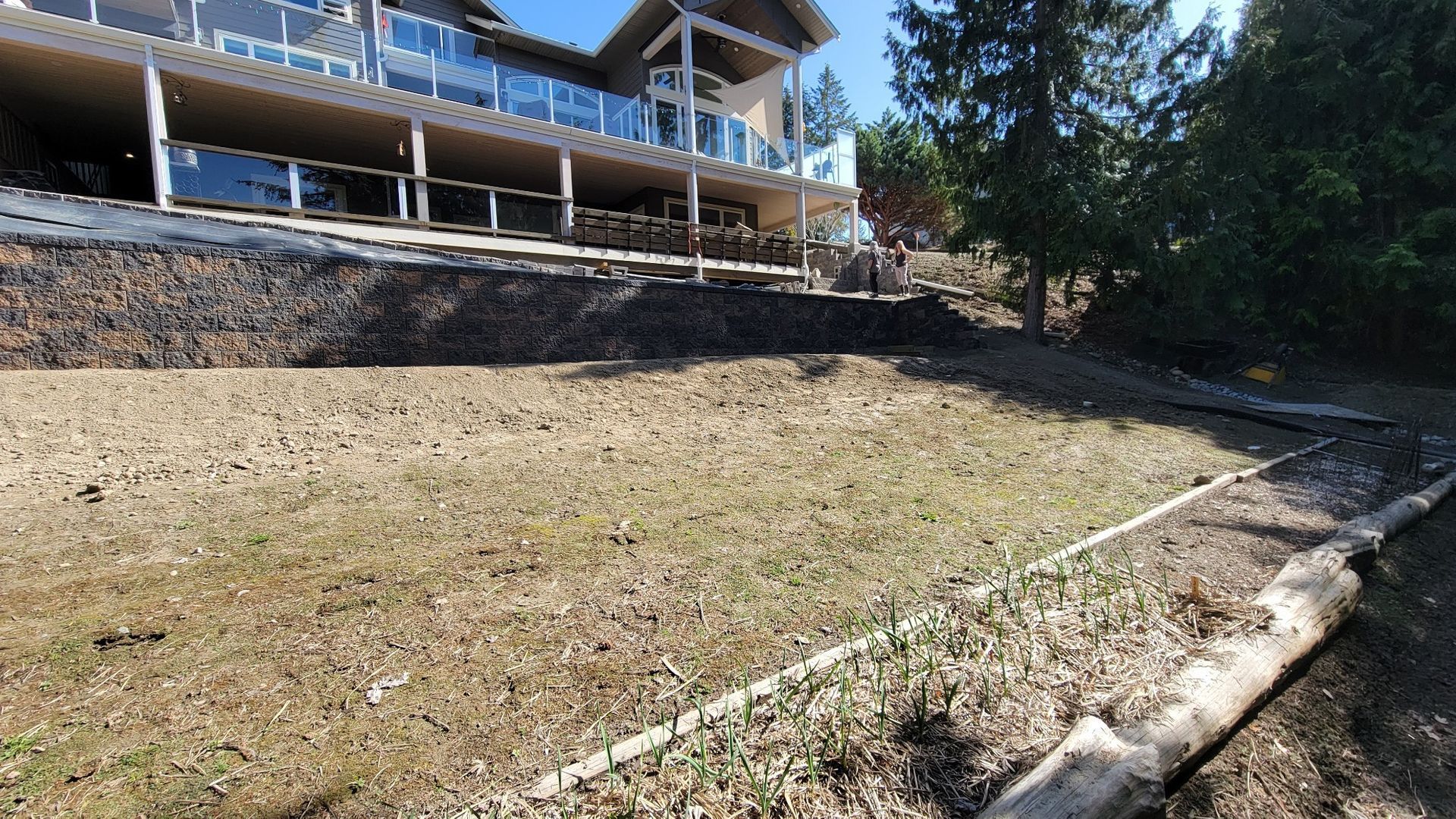 A hillside with a house in the background, showing bare dirt.