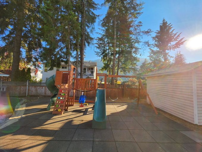 Playground with a slide, swing set, and wooden structures, in a sunny setting.