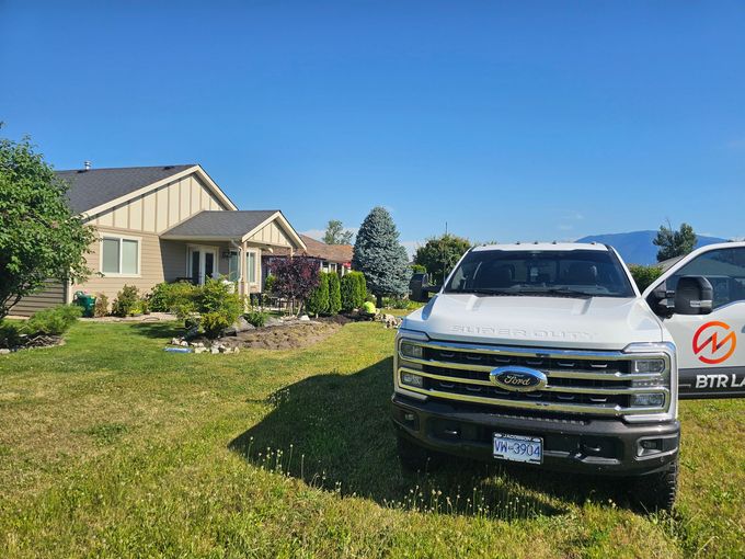 White Ford truck parked in front of a house with green grass and a blue sky.