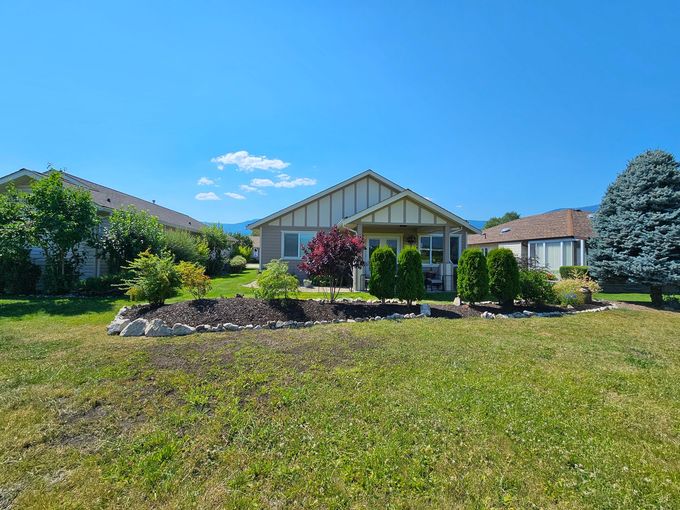 A single-story house with a well-kept lawn and garden, under a clear blue sky.