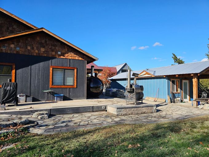 Buildings with a patio, a grill, and outdoor seating on a sunny day.
