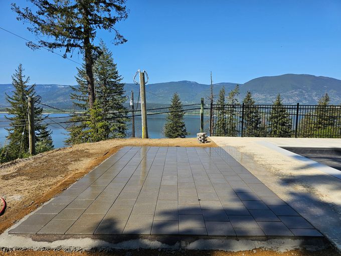 Patio made of grey pavers with lake and mountain view. Sunny day.